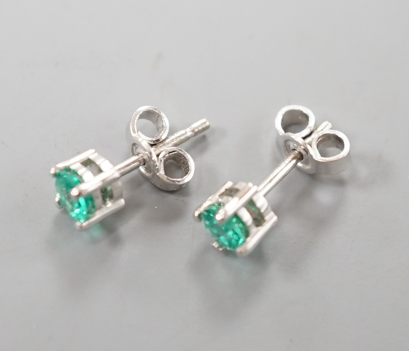 A pair of 750 white metal and solitaire emerald set ear studs, gross weight 1.5 grams, stone diameter approx. 4.2mm.